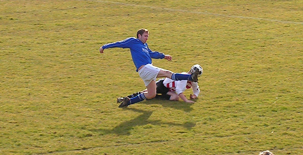 McDermont tries his hardest to boot a Traveller's player in the head when clearing the ball.
